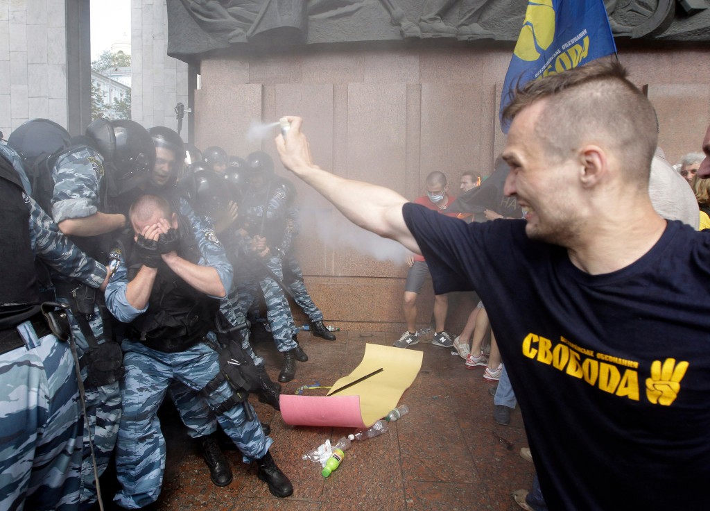 En mand med en t-shirt fra den fascistiske bevægelse Svoboda overfalder betjente med peberspray. 